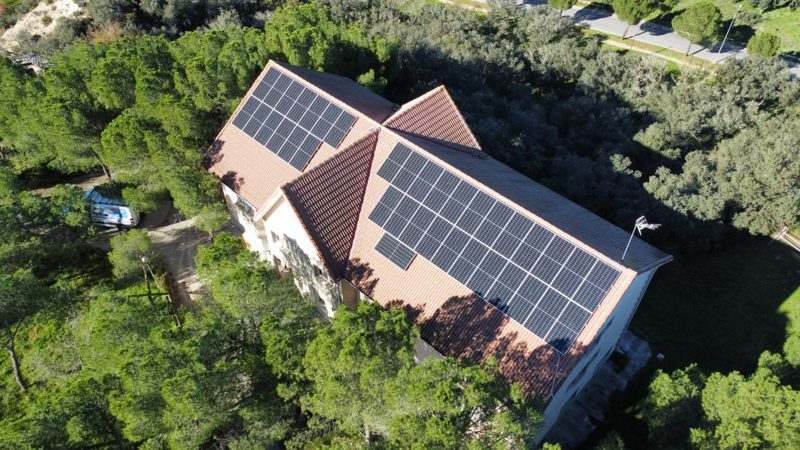 Vivienda unifamiliar con placas solares en el tejado de teja, rodeada de árboles